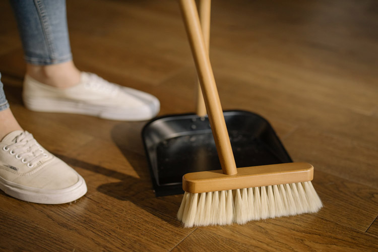 A person sweeping dust into a dust pan.