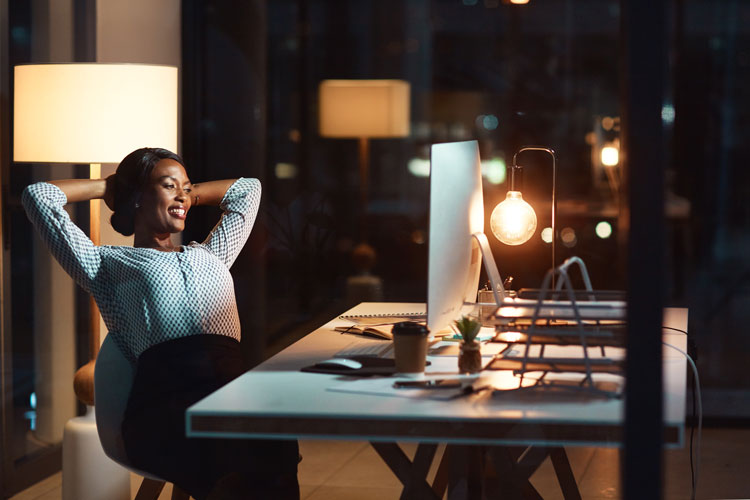 Woman working late but looking happy with her productivity